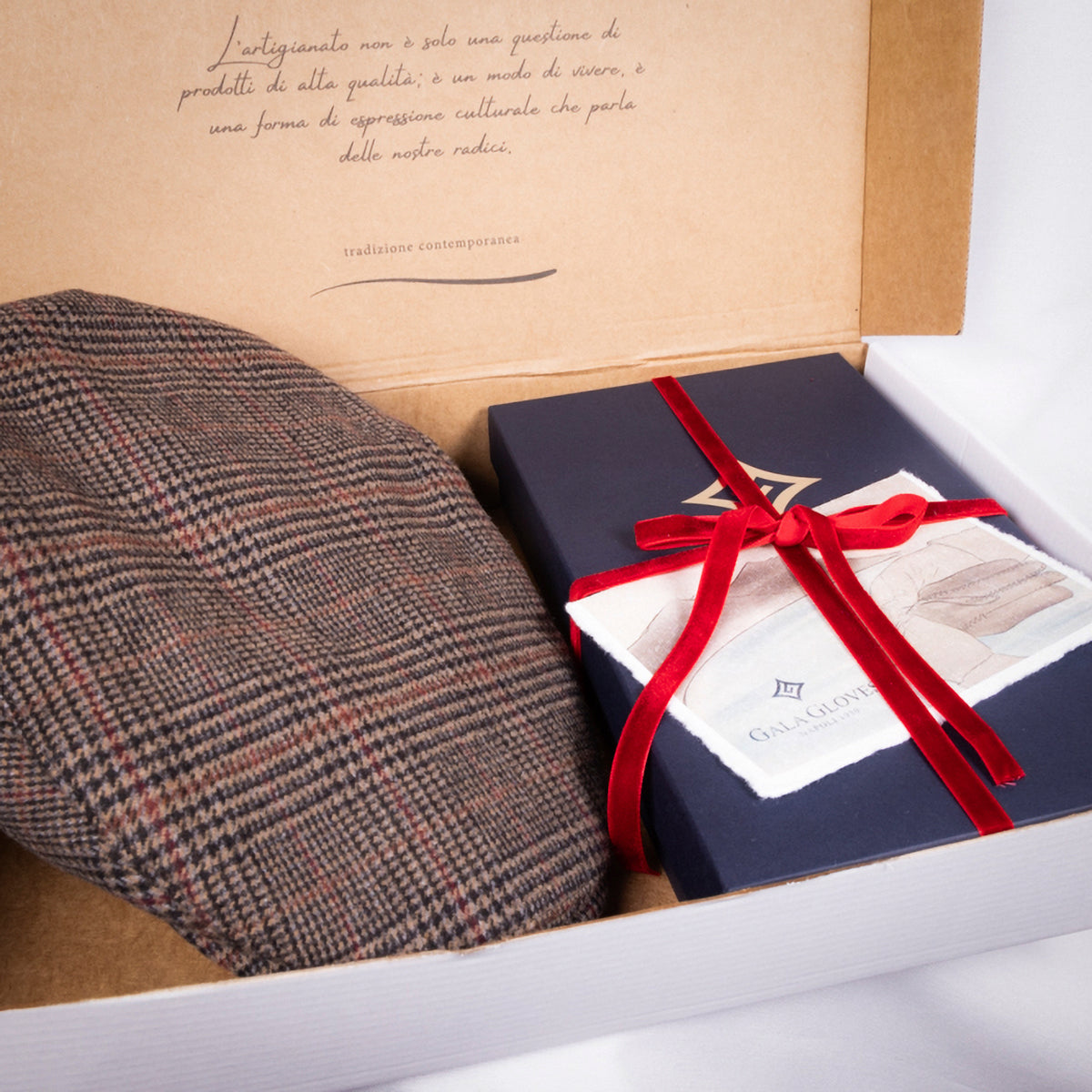 Elegant houndstooth cap nestled beside a beautifully wrapped Gala Gloves box, accented with a red ribbon.