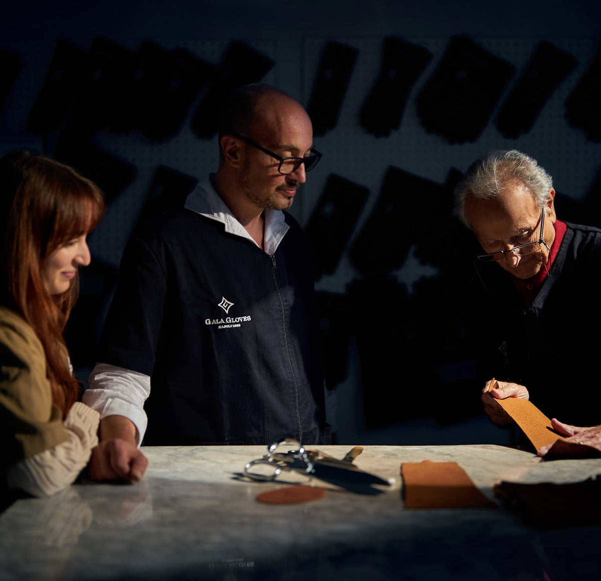 Artisans collaborating on a custom leather glove design at the Gala workshop in Naples