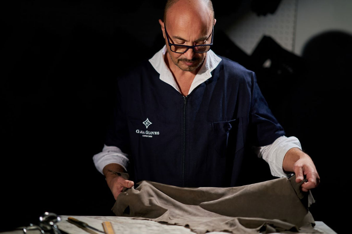 Alessandro Pellone examining soft taupe leather, showcasing meticulous attention to detail in the creation of luxury Italian gloves.