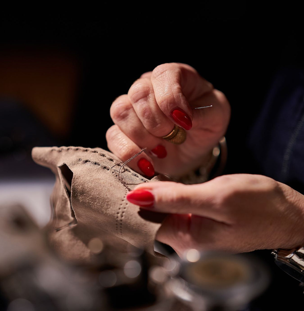 Artisan hand-stitching a soft taupe leather glove, showcasing meticulous Italian craftsmanship and attention to detail.