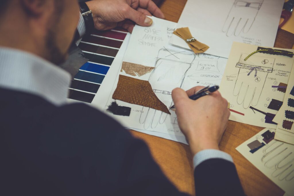 Alessandro Pellone sketches and leather swatches on a table, showcasing the design process for luxury Italian gloves.