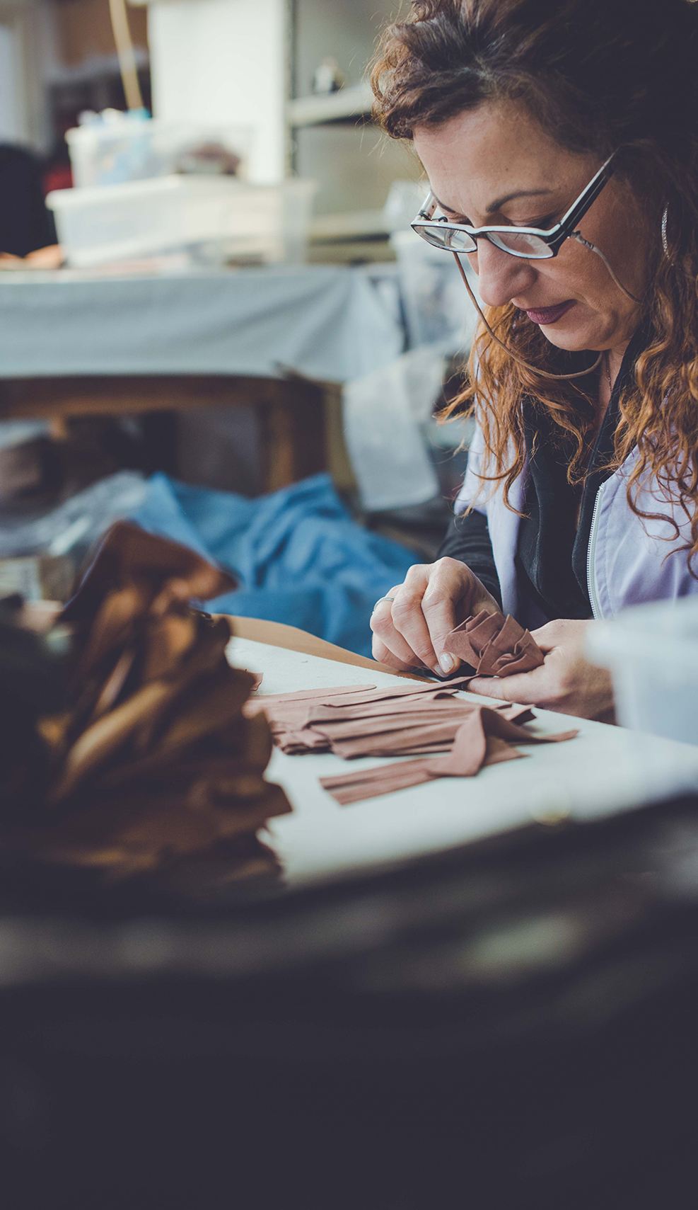 Artisan delicately assembling rich brown leather pieces, showcasing the meticulous craftsmanship behind Gala Gloves.
