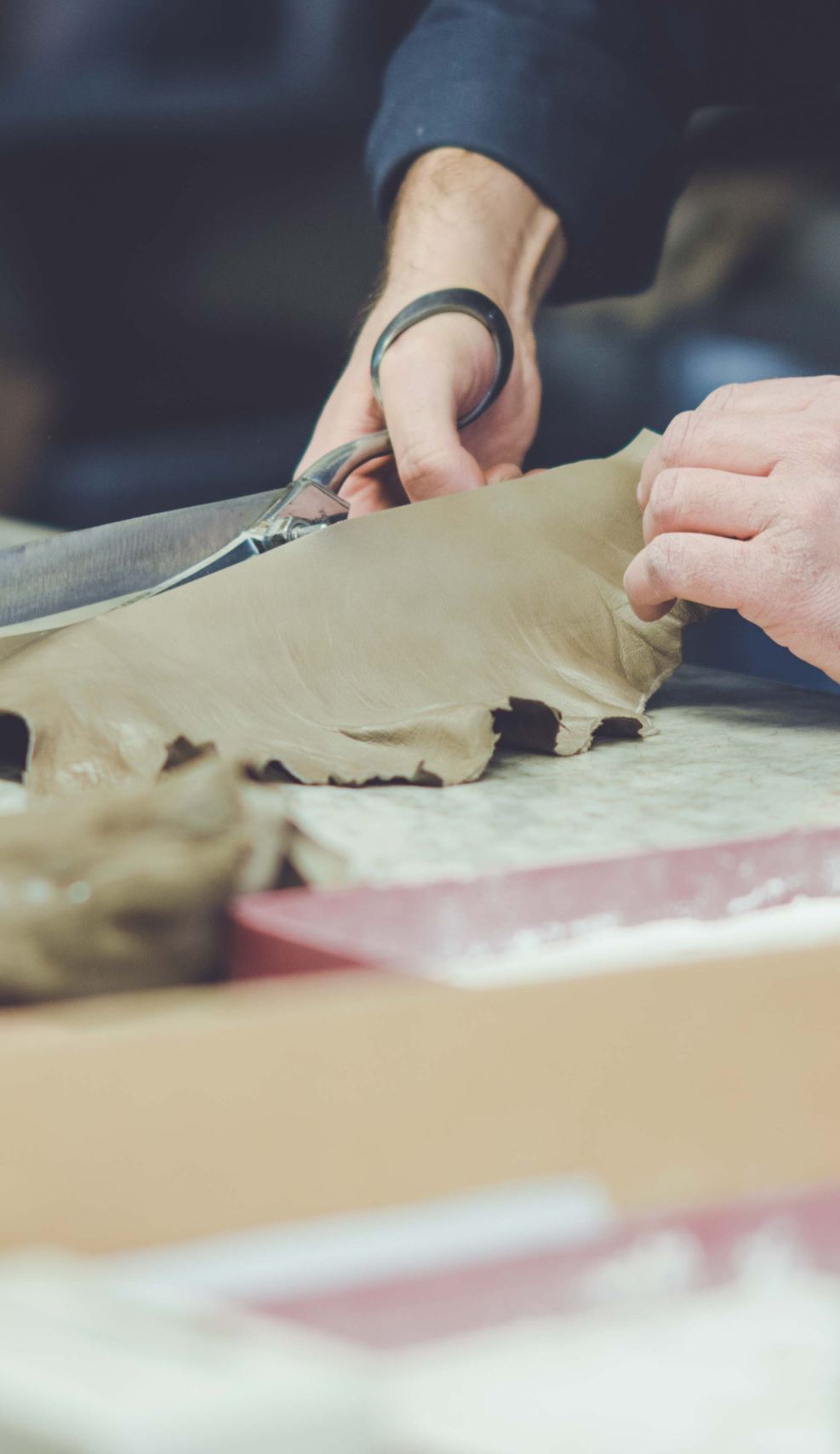 Artisan hands skillfully cutting soft, taupe leather for luxury glove crafting, showcasing Italian craftsmanship and attention to detail. di